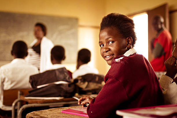 South African girl (from the Xhosa tribe) works on her studies at an old worn desk in a class room in the Transkei region of rural South Africa.